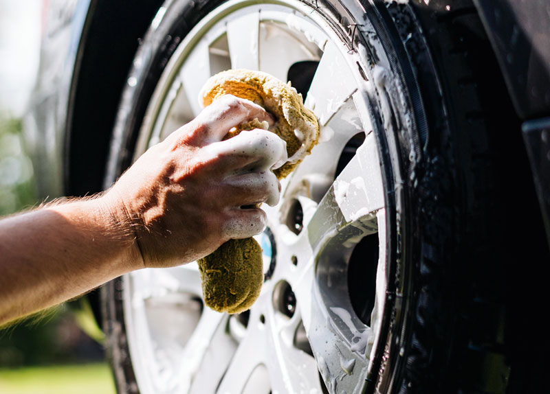 Car wheel being washed with a yellow sponge