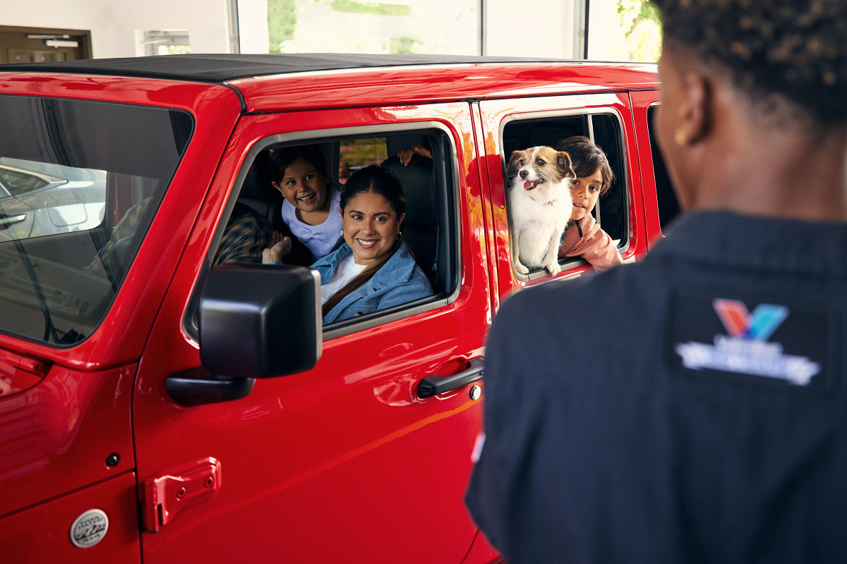 Certified Valvoline Instant Oil technician interacting with a family in a red vehicle